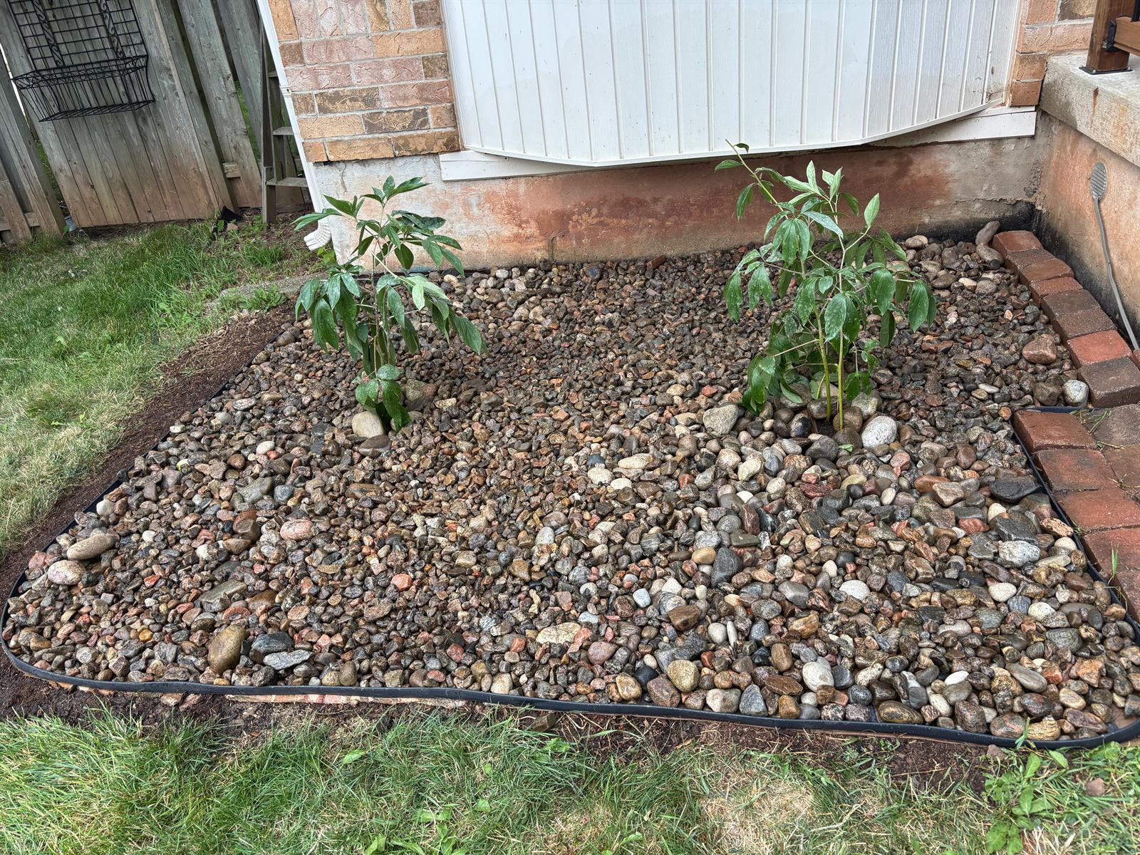 Fresh garden bed landscaping, mulch and stone placement, and clean edging